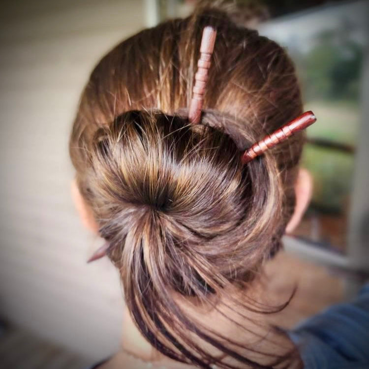 Close-up of a person's hair styled in an updo with decorative hairpins.