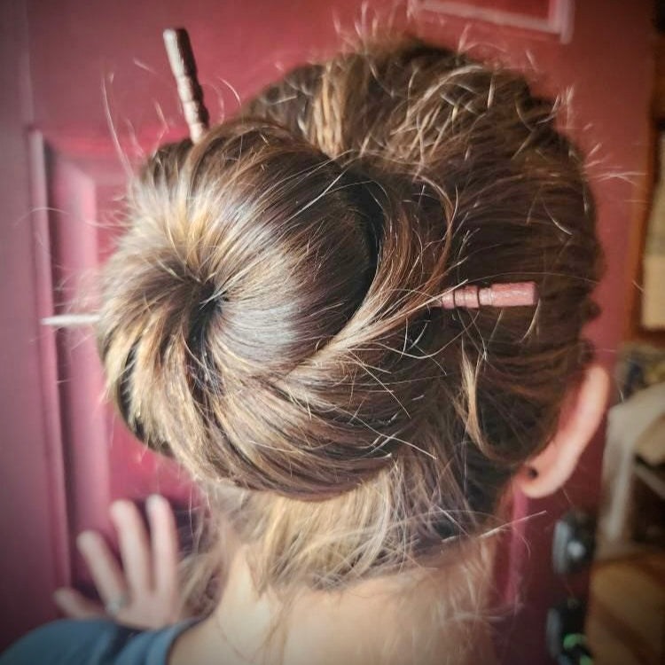 Person with a bun in their hair against a red door background