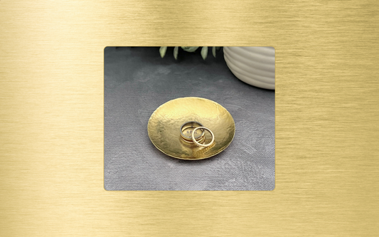 Handcrafted hammered brass ring dish shown with wedding rings and stamped with "I still do" in the center