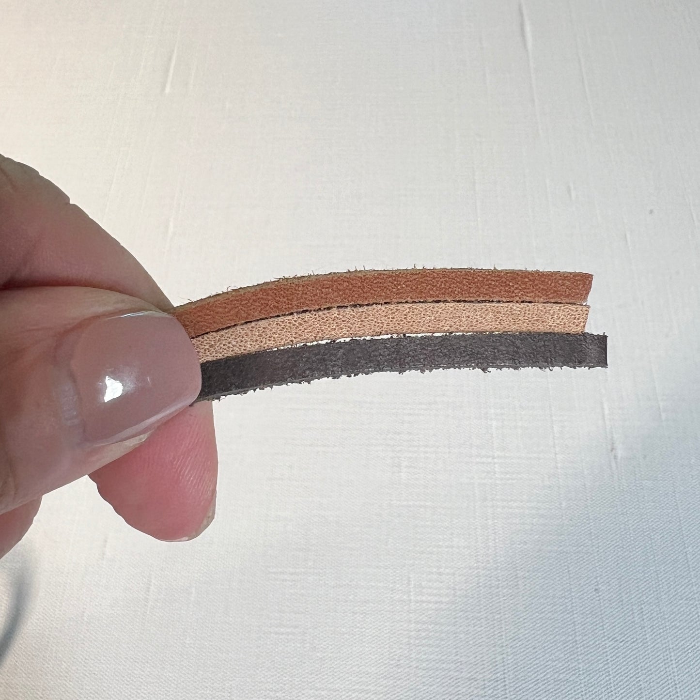 hand holding light, medium and dark brown leather cord